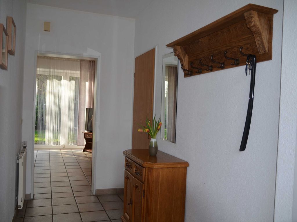 Herzlich Willkommen! Flur Erdgeschoss Einladender Flur einer Ferienwohnung mit Holzkommode, Wandgarderobe und Blick in das lichtdurchflutete Wohnzimmer mit Terrasse.