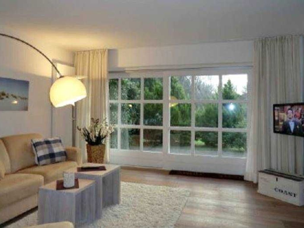 Blick in das helle Wohnzimmer mit Terrassenausgang und Flat-TV
