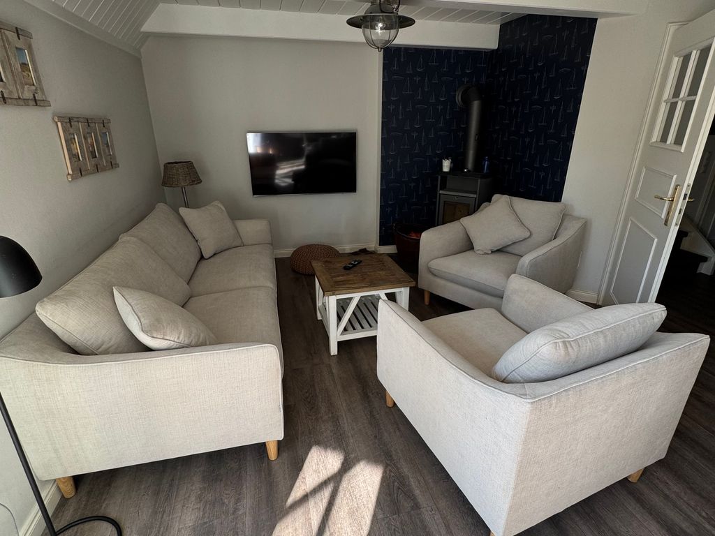 Gemütlicher Wohnbereich mit Flat-TV und Kaminofen