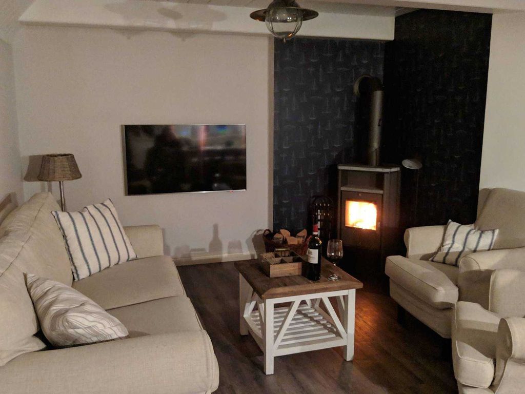 Gemütlicher Wohnbereich mit Flat-TV und Kaminofen