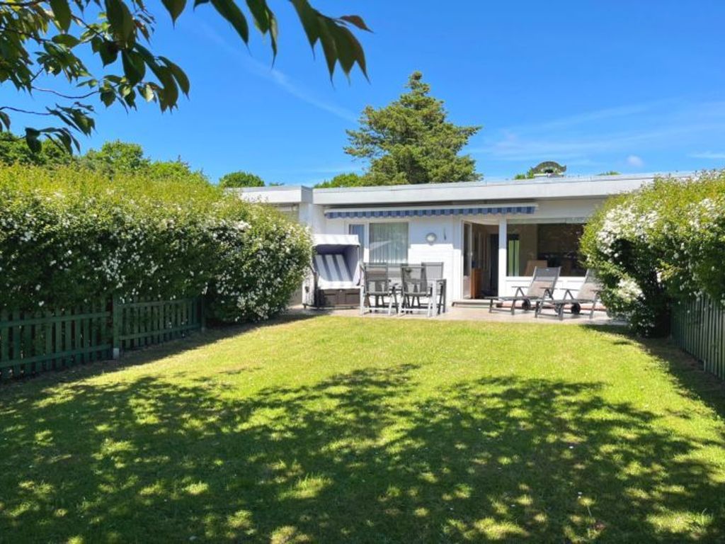 Die Terrassenansicht vom Garten. Der Garten ist vollständig eingezäunt und verfügt über einen Strandkorb und Gartenmöbel.