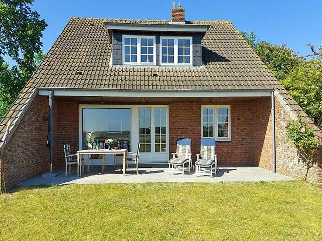 Die Gartenansicht des Ferienhauses im Westerheideweg 11 mit Südterrasse und Garten.