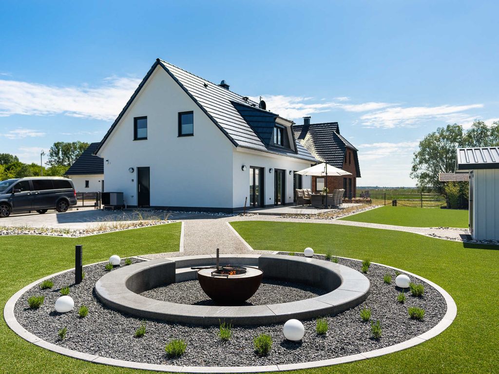 Das Ferienhaus Josefine im Ostseebad Karlshagen auf der Insel Usedom. Eine Außenansicht mit gepflegtem Garten, Terrasse, Feuerstelle und gepflastertem Zugang.