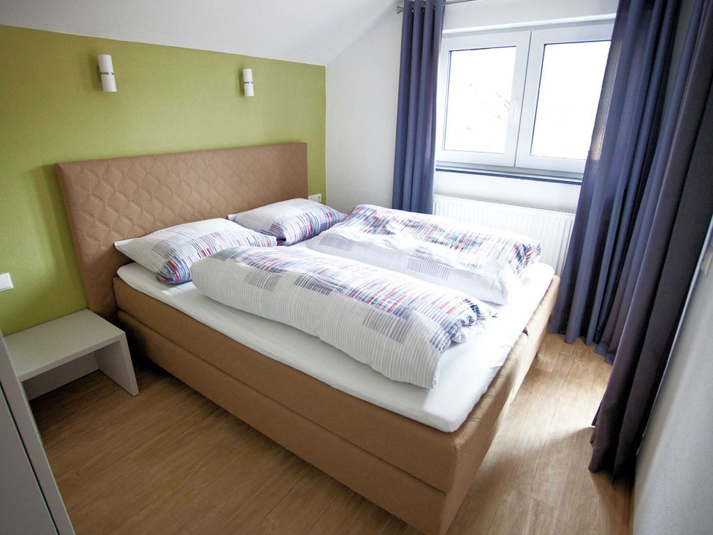 Schlafzimmer mit Boxspringbett und Zugang zur Loggia