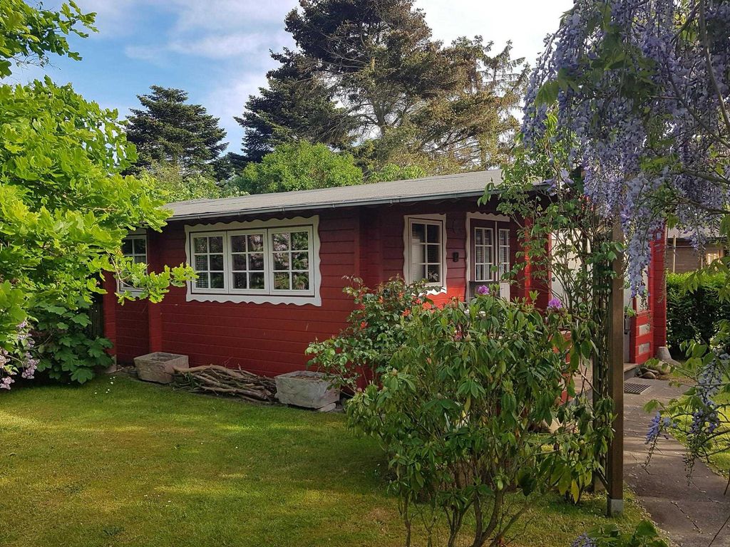Durch den Garten, vorbei an Rosen und altem Baumbestand, gelangen Sie ins Blockhaus Meise 1. Es ist ein massives Holzhaus aus 7 cm dicken Fichtenbohlen. Vom Sitzplatz vor dem Haus genießen Sie den Blick in den Garten. Zum Strand sind es zu Fuß knapp 10 Minuten.