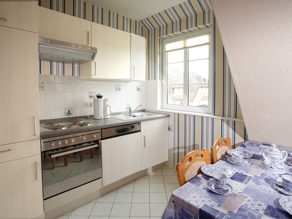 In der Küche befindet sich ein Esstisch, 4-Plattenherd, Backofen, Kühlschrank mit kleinem Gefrierfach sowie Wasserkocher und Kaffeemaschine.