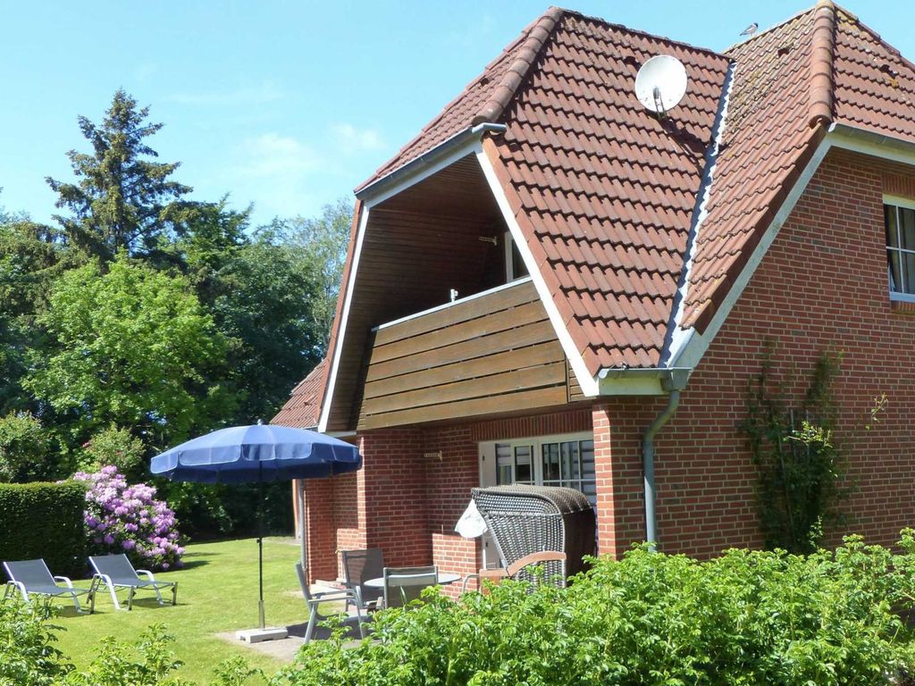 Sonnige Südterrasse mit Strandkorb und gepflegtem Garten mit Rhododendren, eingebettet vom inseltypischen Friesenwall.