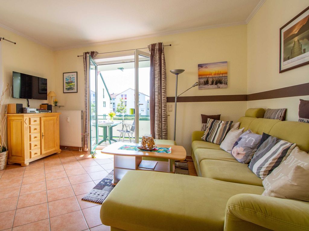 Das gemütliche Wohnzimmer mit Couchgarnitur, Flachbild-TV und Zugang zum Balkon