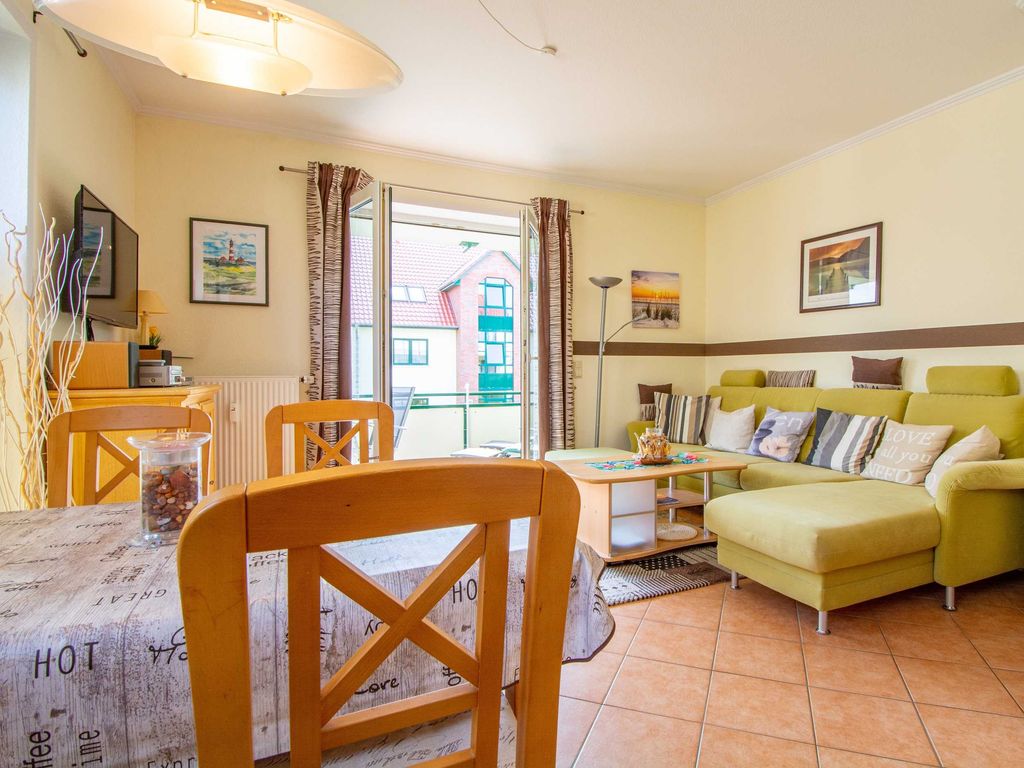 Das gemütliche Wohnzimmer mit Essecke, Couchgarnitur, Flachbild-TV und Zugang zum Balkon