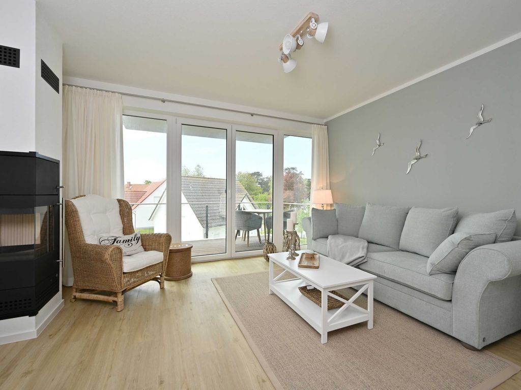 Haus Bodden-Markt Glowe: Wohnbereich mit Kaminofen, Sofa und Zugang zum Balkon