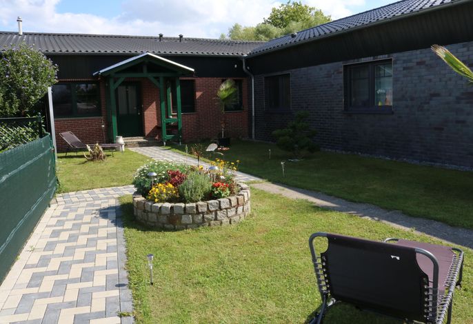 Gartenbereich mit Blumeninsel und Liegen zum Entspannen