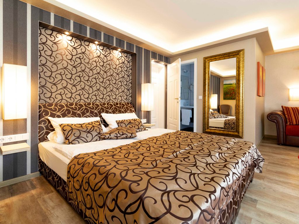 Großes Schlafzimmer mit modernem Hotel-Boxspringbett und angrenzendem Bad