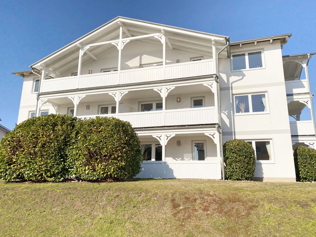 Villa Fernsicht Göhren – weiße Villa im Bäderstil mit weißen Holzveranden über drei Etagen, davor ein Rasenhang