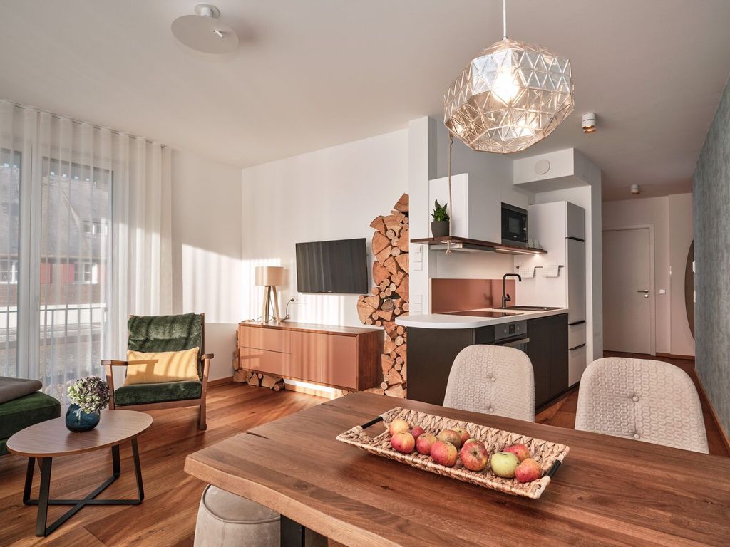 Helles Wohnzimmer mit offener Küche und Zugang zum Balkon.