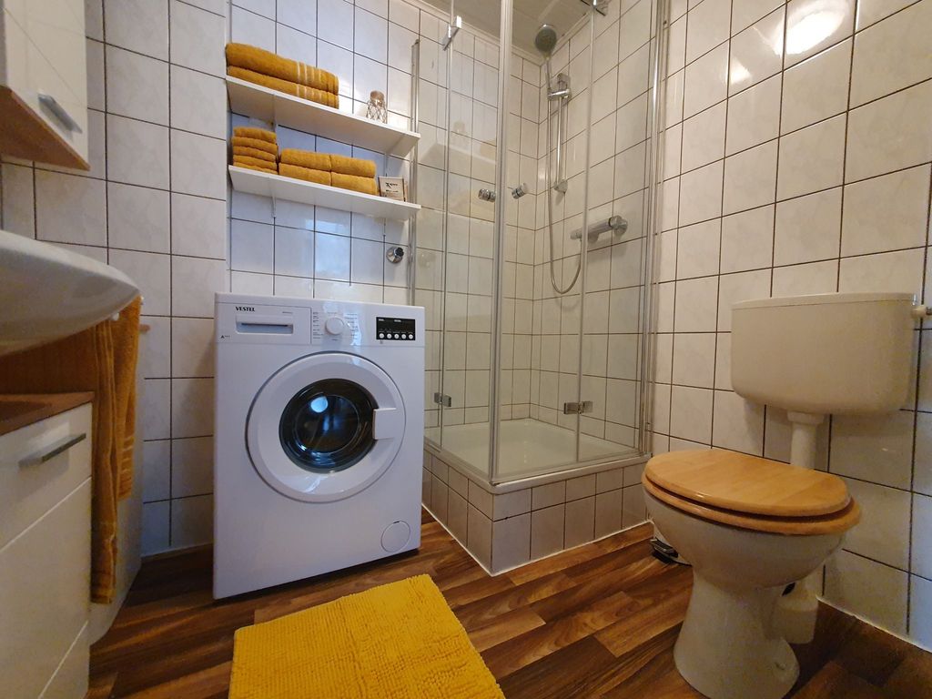 Ferienwohnung im Fehnland - Badezimmer mit Waschtisch, Waschmaschine, Dusche und Toilette