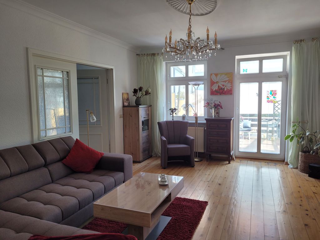Wohnzimmer mit großzügigem Sofa und Zugang zum Wintergarten