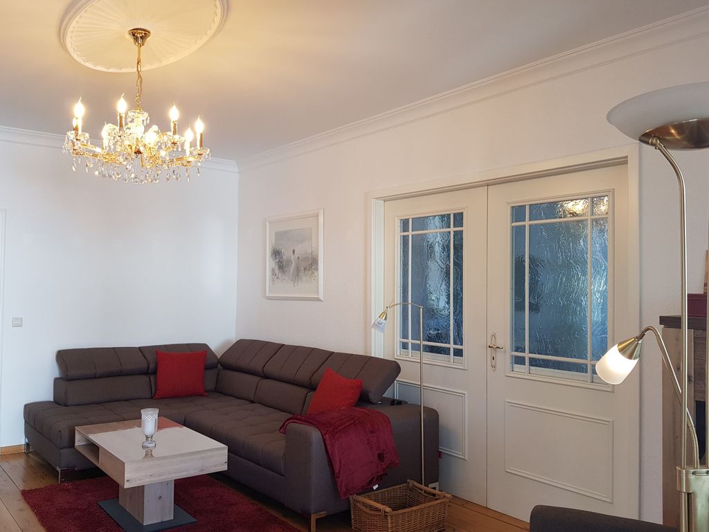 Wohnzimmer mit großzügigem Sofa und Flügeltür zum Schlafzimmer 2