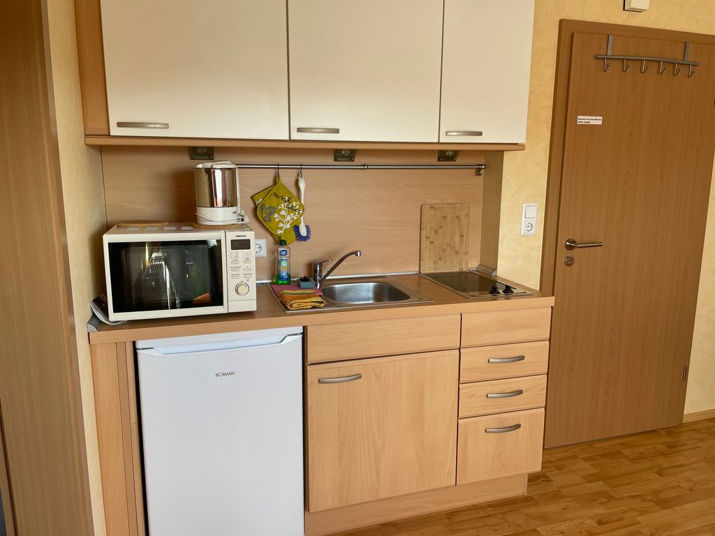 Küchenzeile mit Kühlschrank, Mikrowelle, Spüle und Ceranfeld