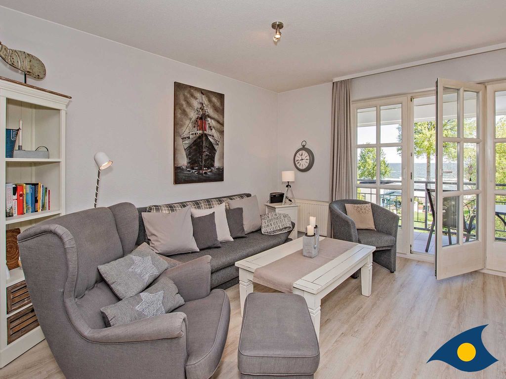 liebevoll eingerichtetes Wohnzimmer mit offener Küche und Zugang zum überdachten Balkon