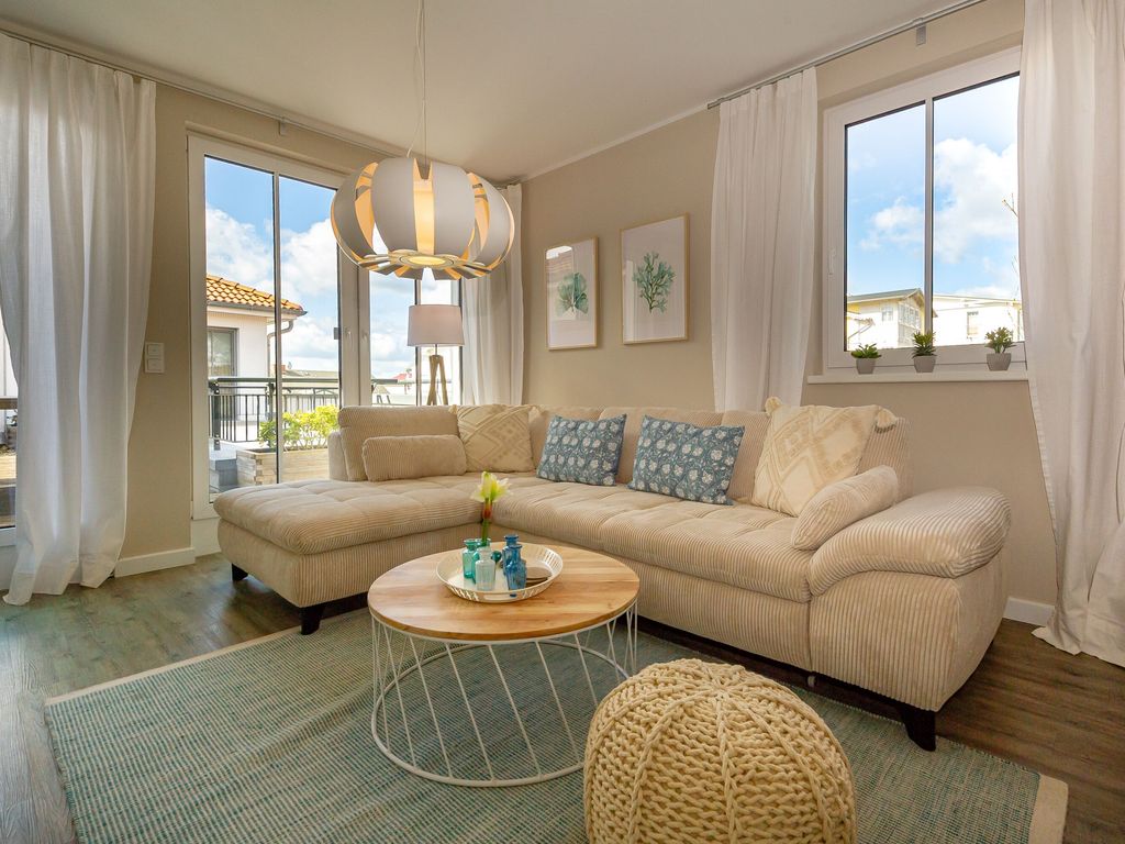 Villa Annika Sellin – helles Wohnzimmer im Penthouse mit Ecksofa, maritimen Kissen und Zugang zur Dachterrasse
