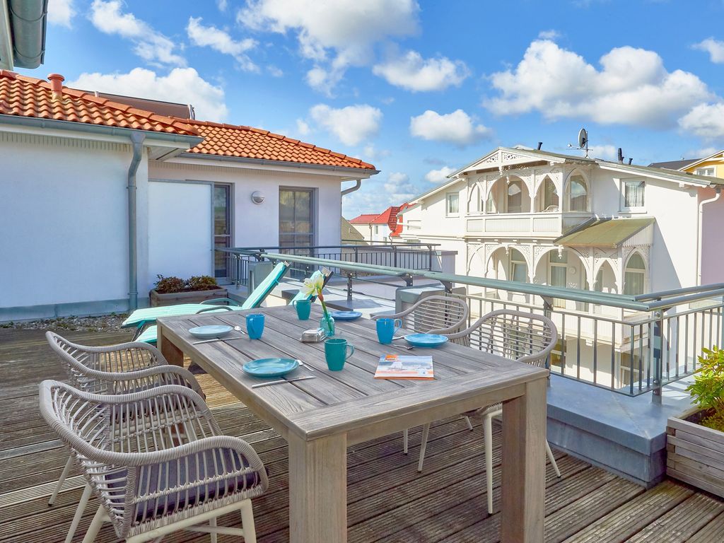 Villa Annika Sellin – Dachterrasse des Penthouse mit Esstisch, Liegen und Blick auf die Nachbarvillen