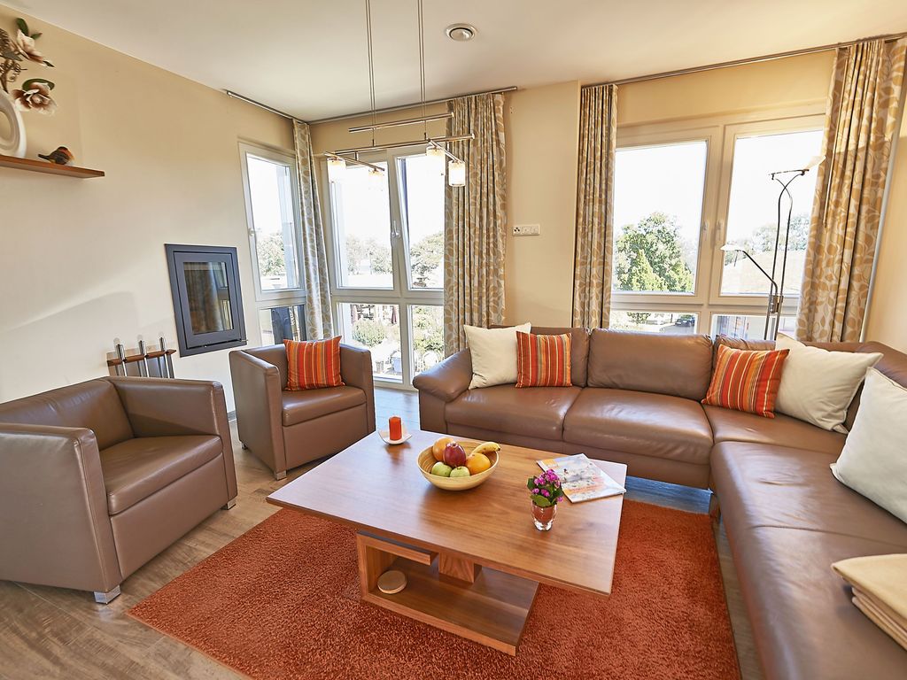 Strandvilla Baabe – Wohnzimmer mit Ledersofa, Kamin und bodentiefen Fenstern