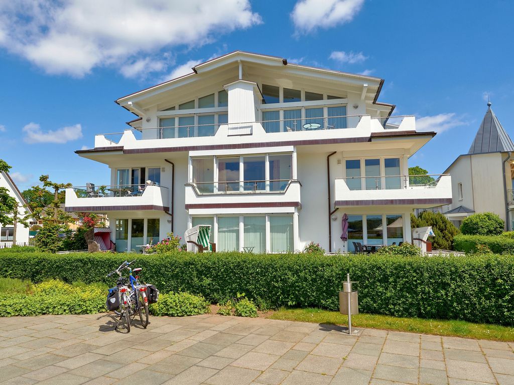 Villa Seerosen Binz – weiße Villa mit Balkonen, Terrassen und Strandkörben hinter der Gartenhecke