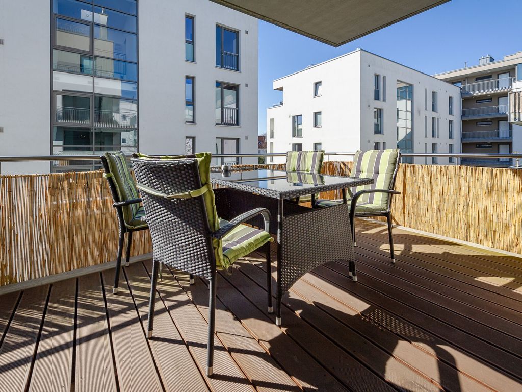 DünenResort Binz – möblierte Holzterrasse einer Ferienwohnung mit Blick in den Innenhof der Anlage