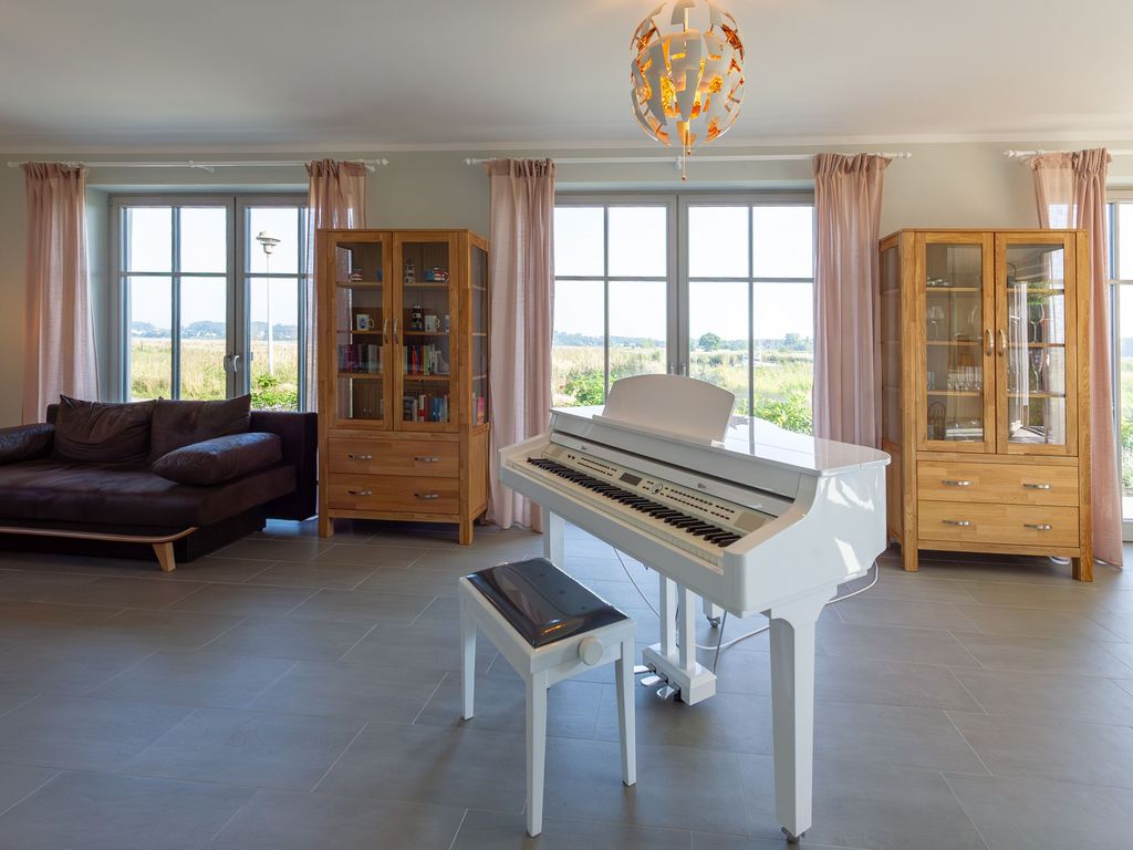 Wohnzimmer mit Flügel, Panoramafenstern und Blick auf die Landschaft