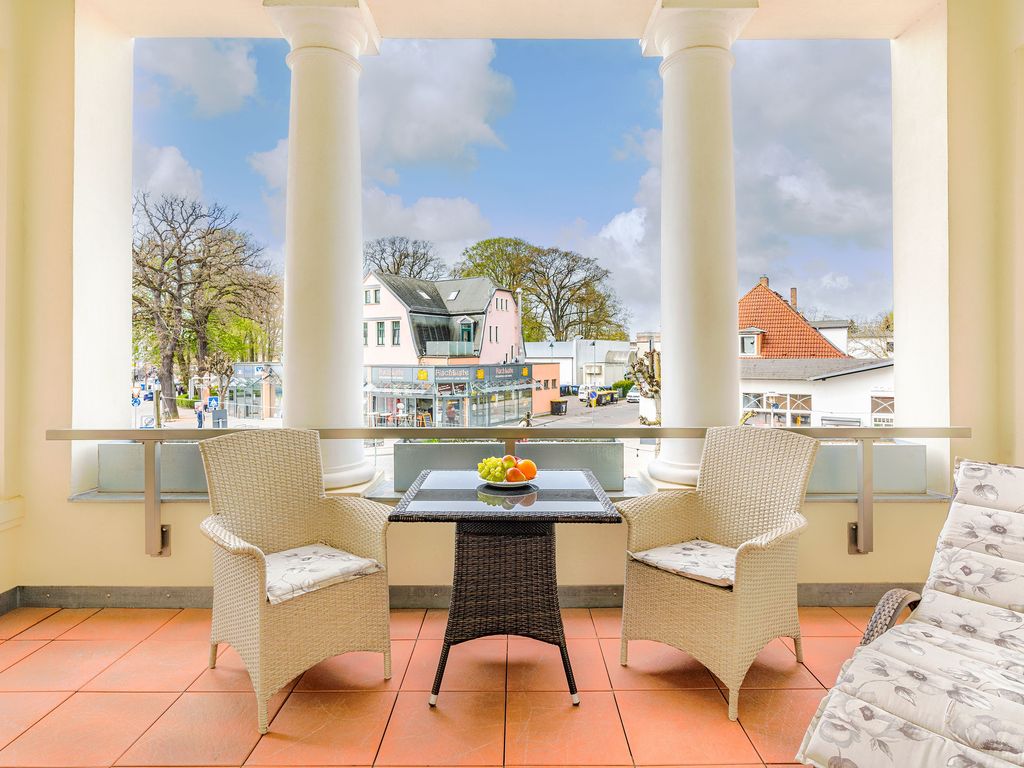 Villa Gruner Zinnowitz – überdachte Säulen-Veranda mit Korbsesseln und Blick auf die Straße im Ortszentrum