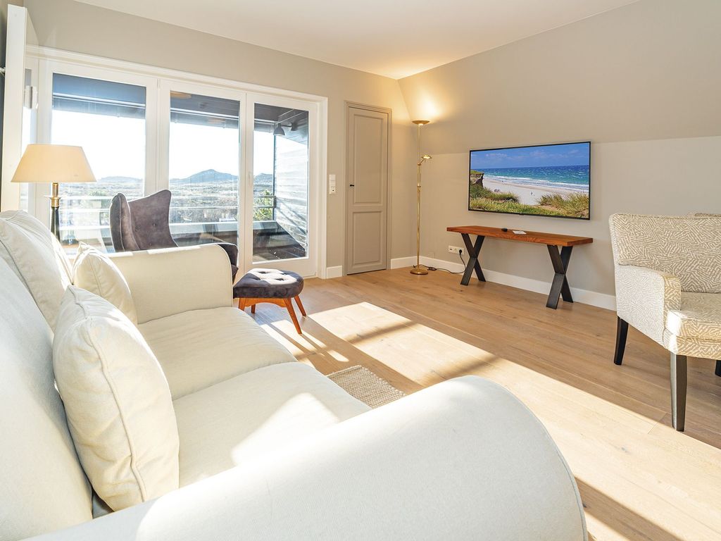 Wohnbereich mit großer Fensterfront und Zugang zum Balkon