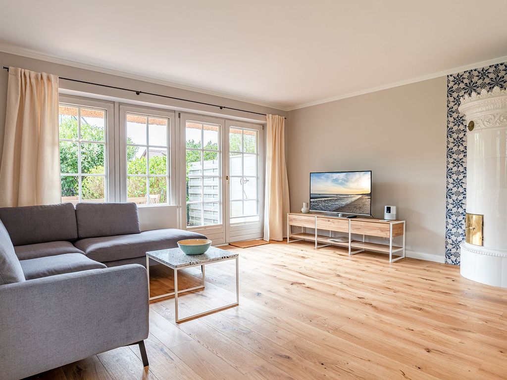 Wohnbereich mit Flat-TV, Kaminofen und einem der Terrassenausgänge