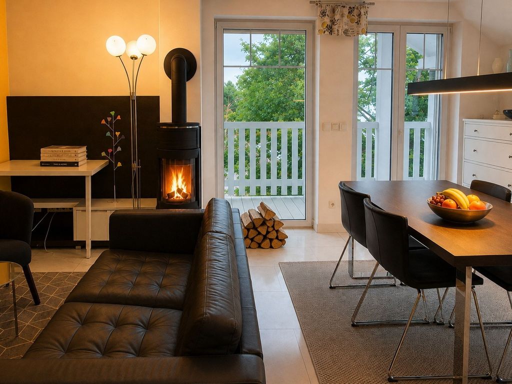 Wohnzimmer mit Kamin und Essbereich und Zugang zu zwei Balkonen.