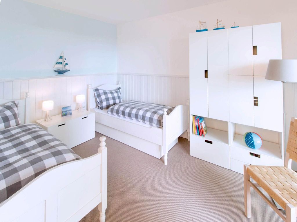 Liebevoll eingerichtetes Kinderzimmer mit zwei Einzelbetten, Schrank und maritimer Dekoration. Ideal für Familienurlaub in einem kinderfreundlichen Ferienhaus.