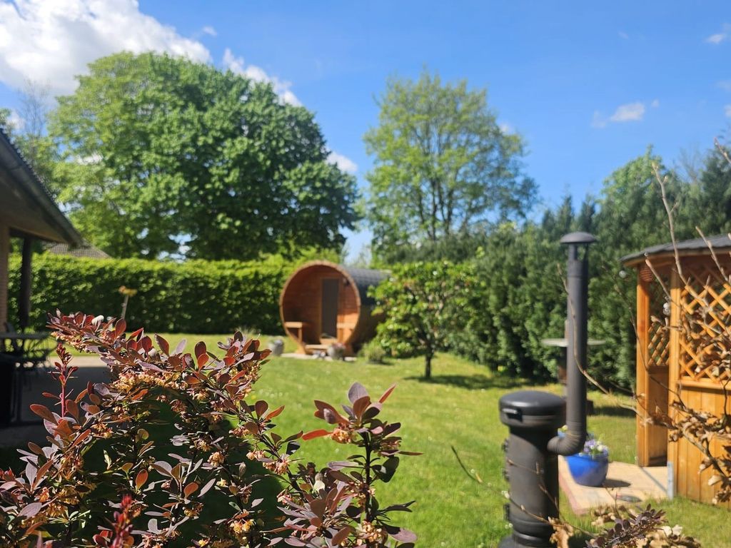 Blick auf das Außengelände mit Saunafass, Grill und Pavillon