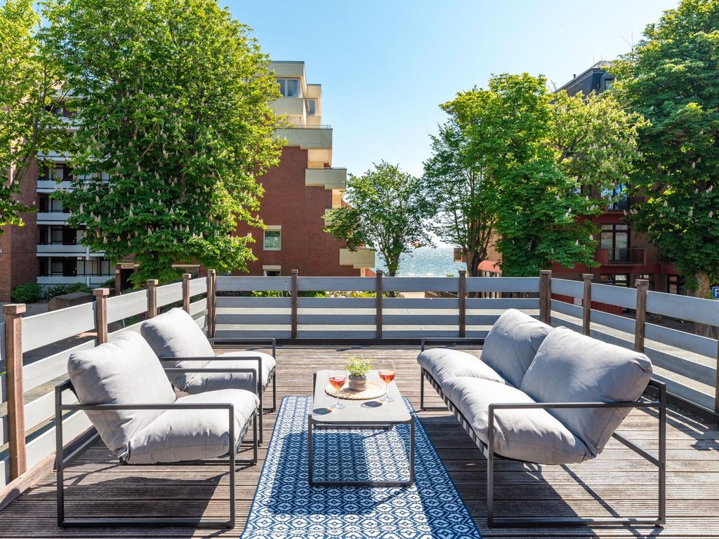 Große Dachterrasse von Utes Huus in Wyk auf Föhr mit Lounge-Möbeln, Blick auf Bäume und seitlichem Meerblick