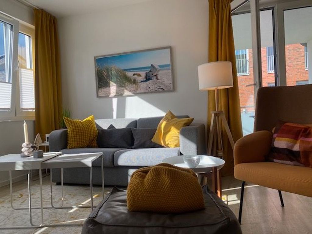 Der helle Wohnraum mit hochwertigem Sofa und modernem Sessel