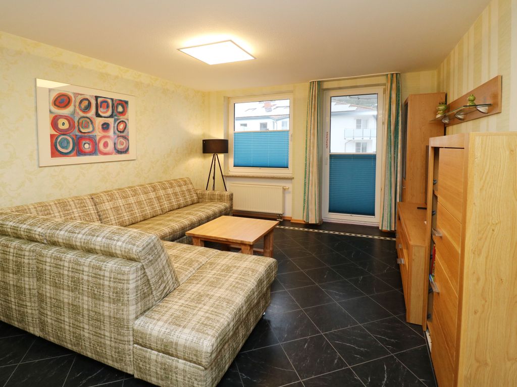 Heller Wohnbereich der Ferienwohnung Q03 im Quartier 18 in Karlshagen mit großzügiger Couch und direktem Zugang zum Balkon auf der Hofseite