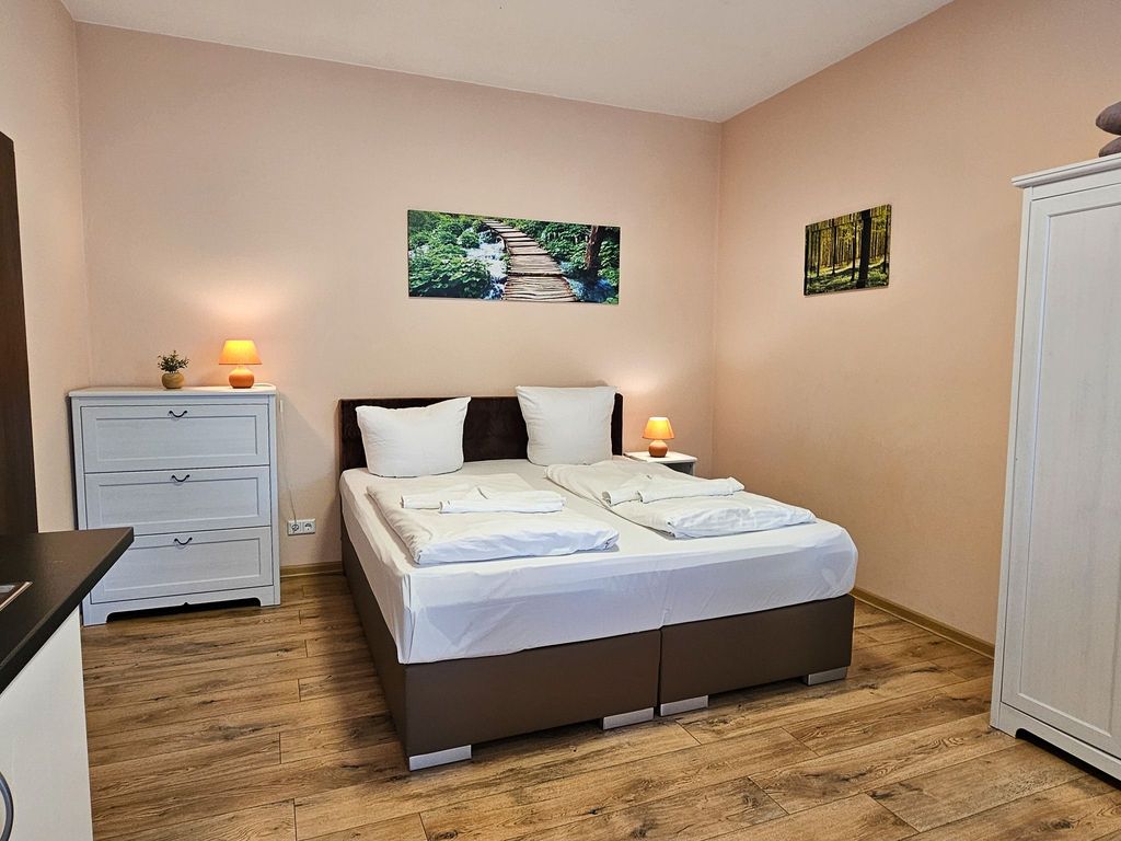 Wohnbereich mit Doppelbett und Küchenzeile sowie Loggia mit Terrassenzugang
