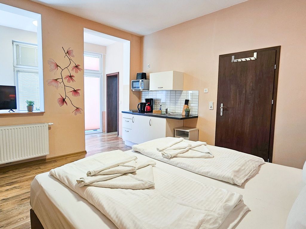 Wohnbereich mit Doppelbett und Küchenzeile sowie Loggia mit Terrassenzugang