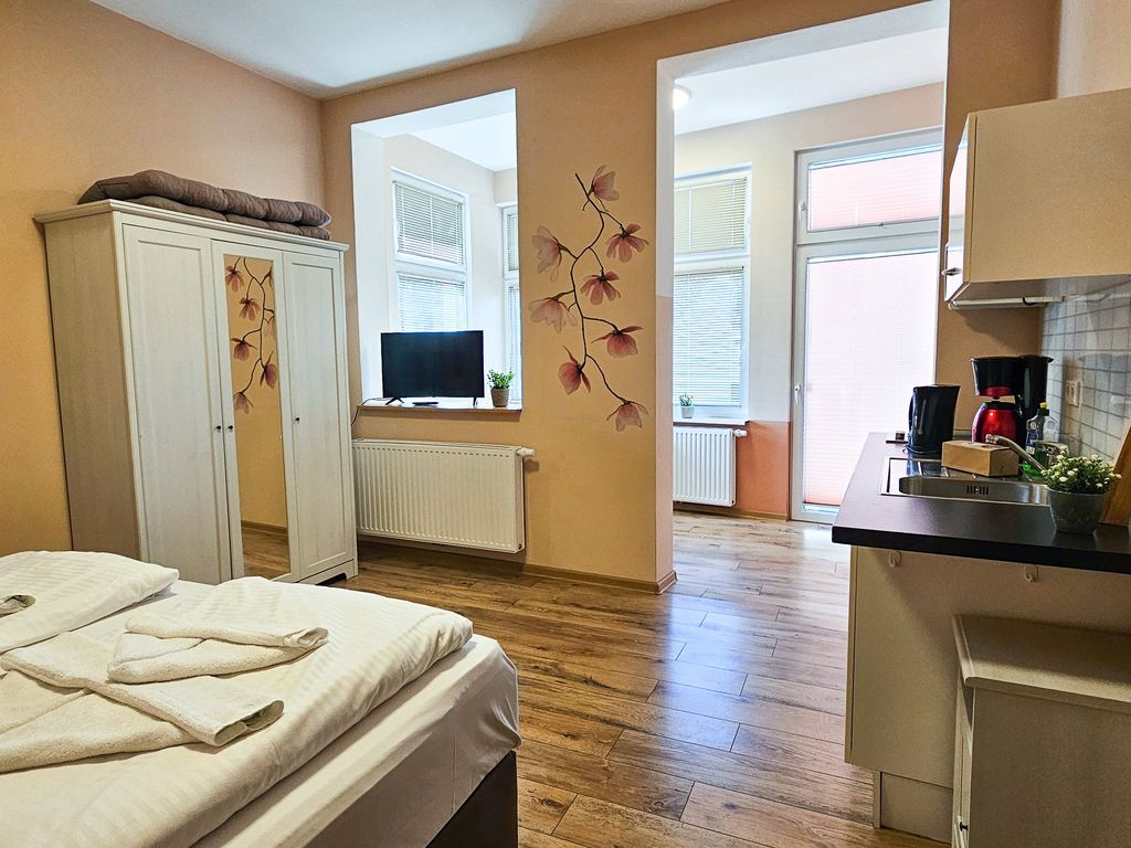 Wohnbereich mit Doppelbett und Küchenzeile sowie Loggia mit Terrassenzugang