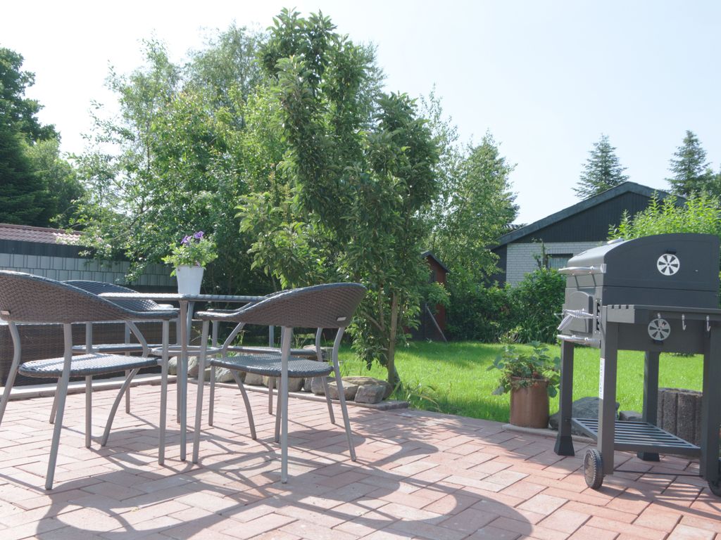 Moderne Terrasse mit Grill und Sitzgruppe im gepflegten Garten  ideal für entspannte Stunden im Grünen und gesellige Grillabende unter freiem Himmel.