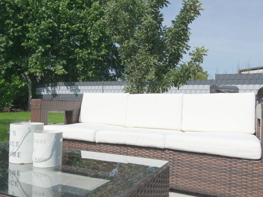 Großzügige Gartencouch mit bequemen Polstern und Glastisch  ideal für entspannte Stunden an der frischen Luft in stilvoller Wohlfühlatmosphäre.