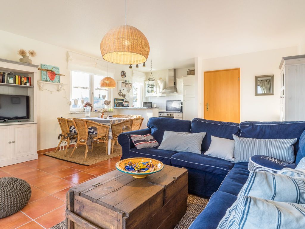 Wohnzimmer mit offener Küche und Zugang zum Balkon