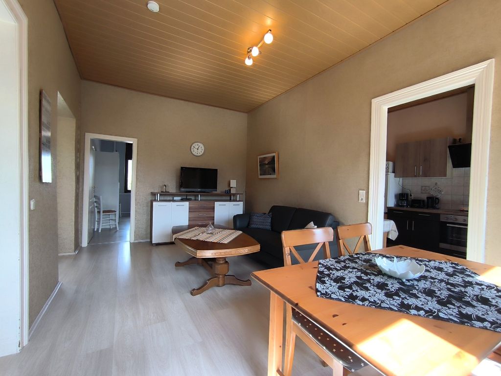 Wohnzimmer mit Sofa, TV und Esstisch