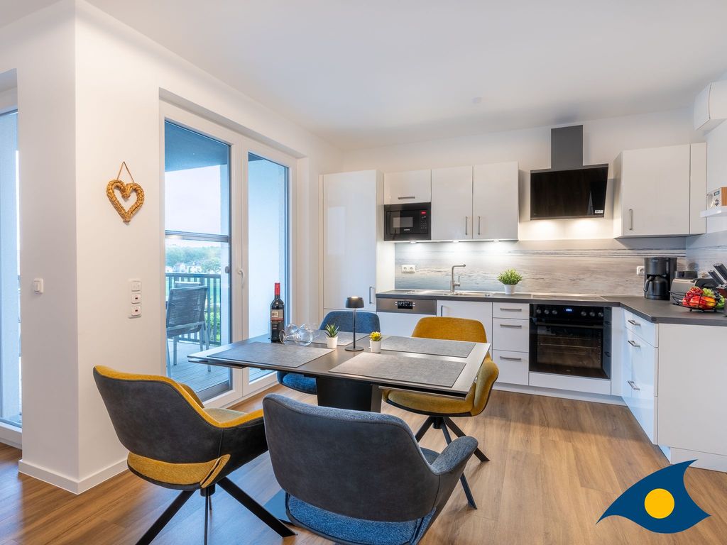 Wohnbereich mit offener Küche und Zugang zum Balkon