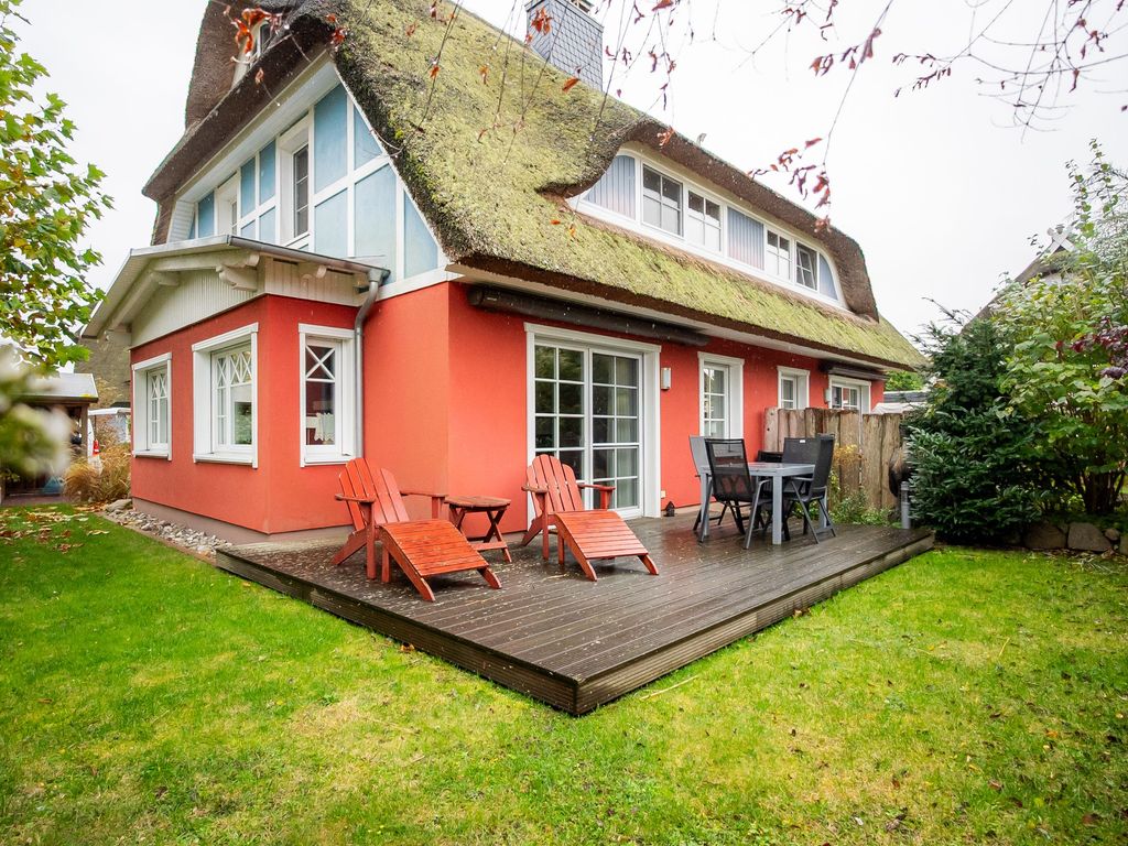 Südwestlich ausgerichtete Holzterrasse mit Sitzmöbeln und Liegestühlen, umgeben von einem gepflegten Garten.
