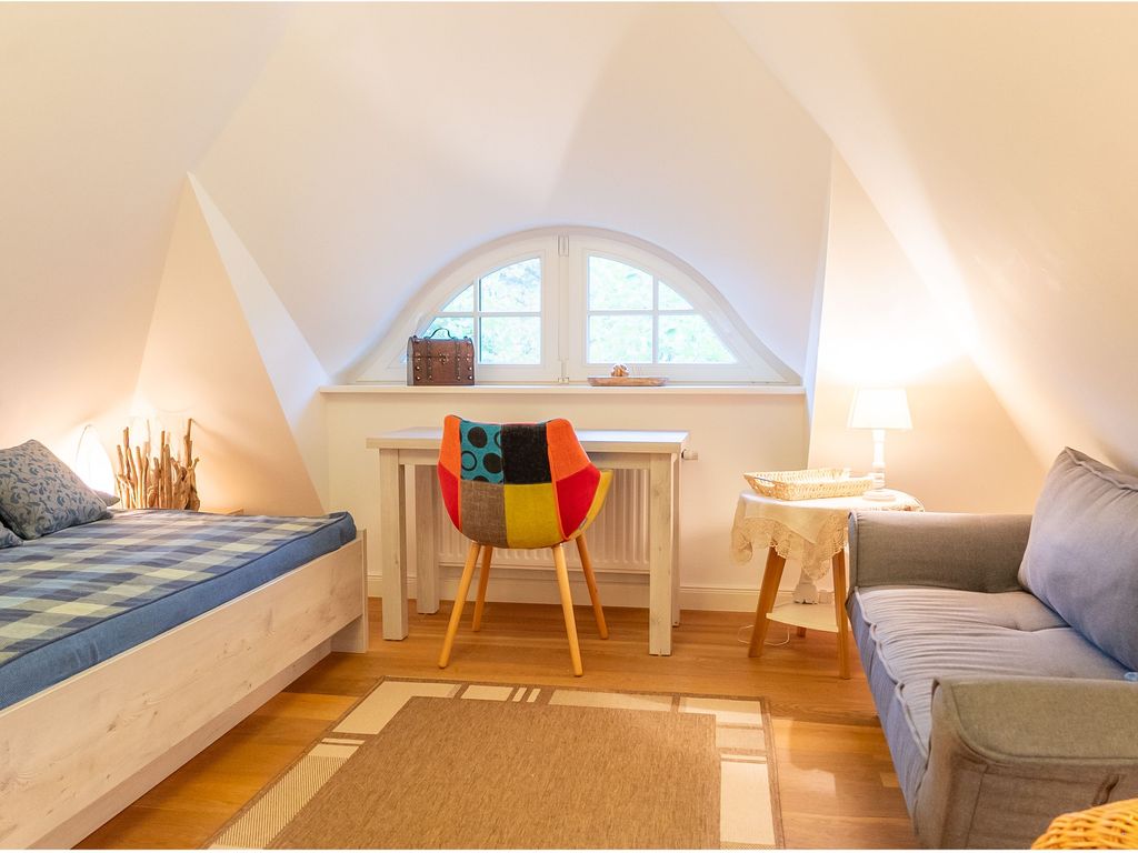 Offenes Studio im Dachgeschoss mit Einzelbett, Sofa und Schreibtisch.