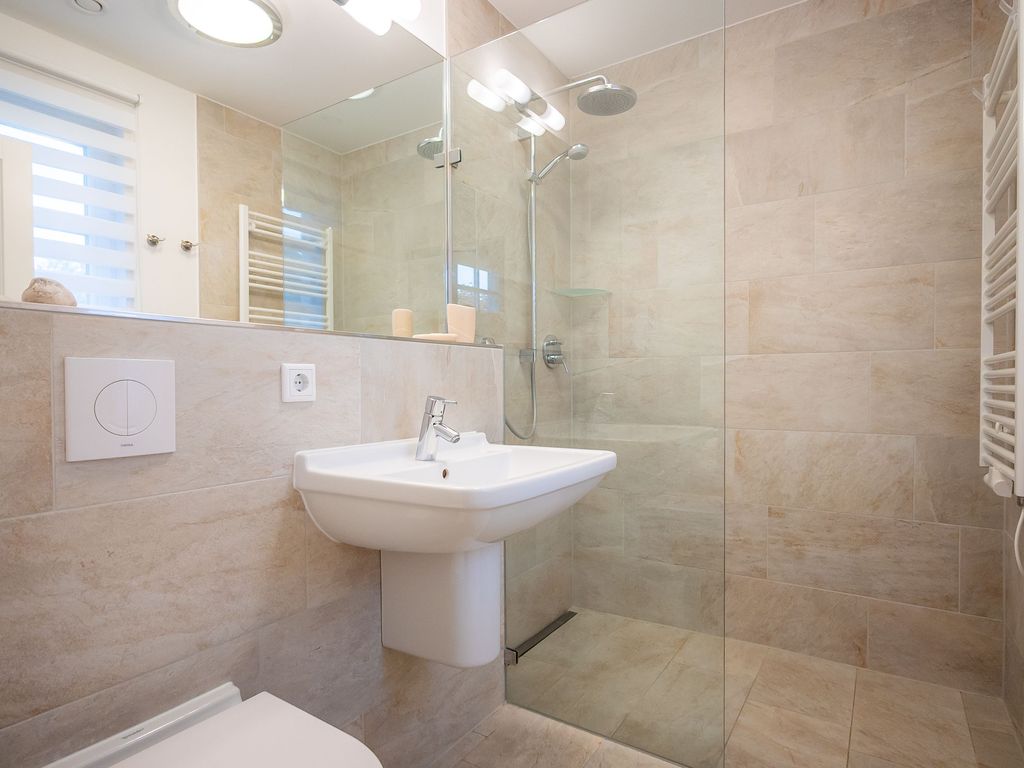 Helles Tageslichtbad im Erdgeschoss mit bodengleicher Dusche, Waschbecken und WC.