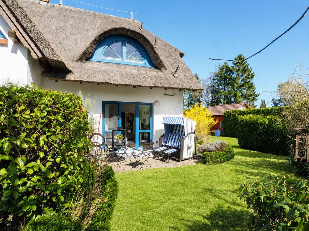 sonnige Gartenterrasse mit Strandkorb, Sitzbereich und viel Grün.